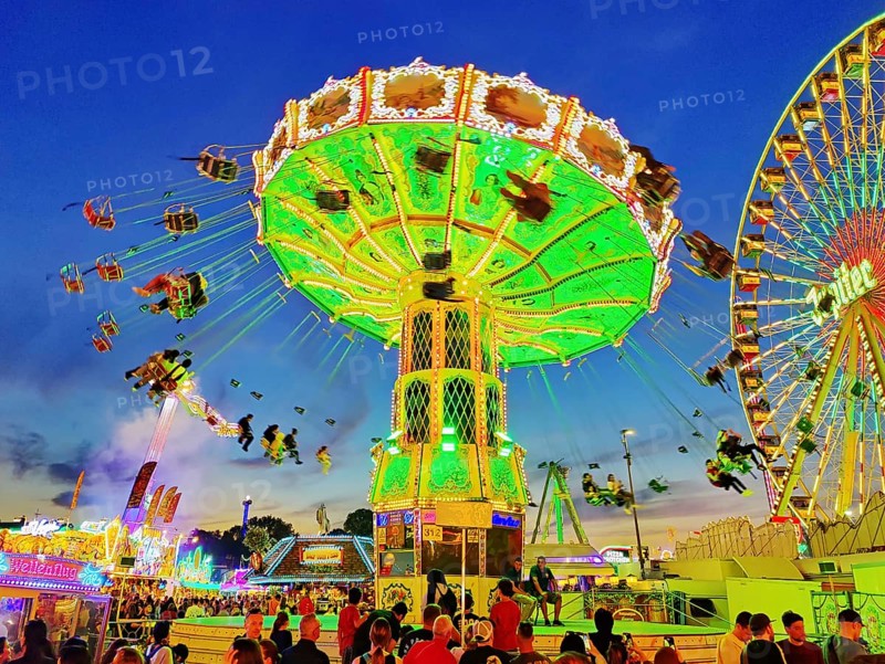 The colourfully illuminated Wellenflug chain carousel and the Ferris wheel in the evening, Cranger Kirmes, Herne, Ruhr area, North Rhine-Westphalia, Germany, Europe