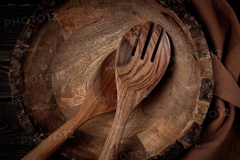 Wooden plate, handmade, with salad spoons, top view, on a wooden table, no people