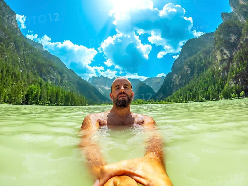 Tourist swimming in the crystal clear waters of lago di landro, surrounded by the breathtaking scenery of the dolomites on a sunny summer day