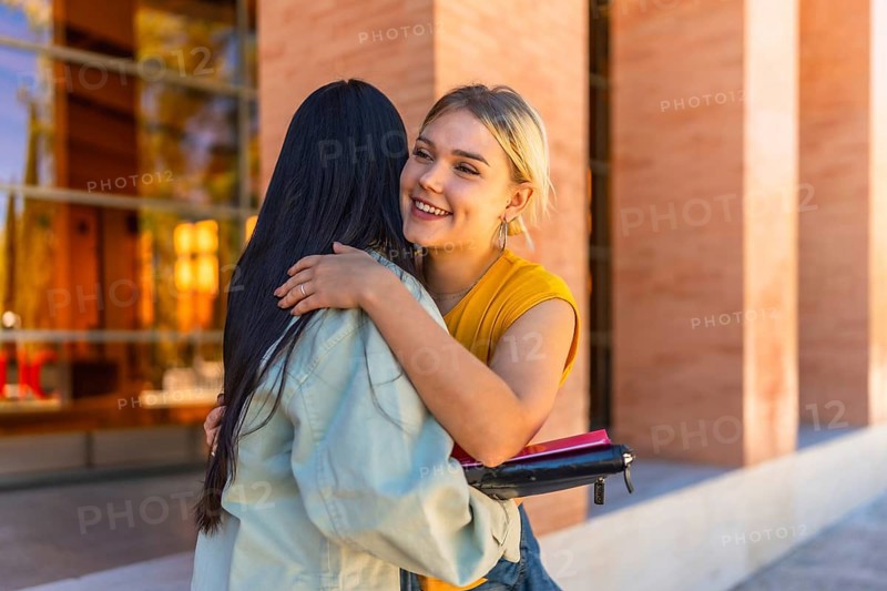 Student greeting a university mate and embracing her at the campus