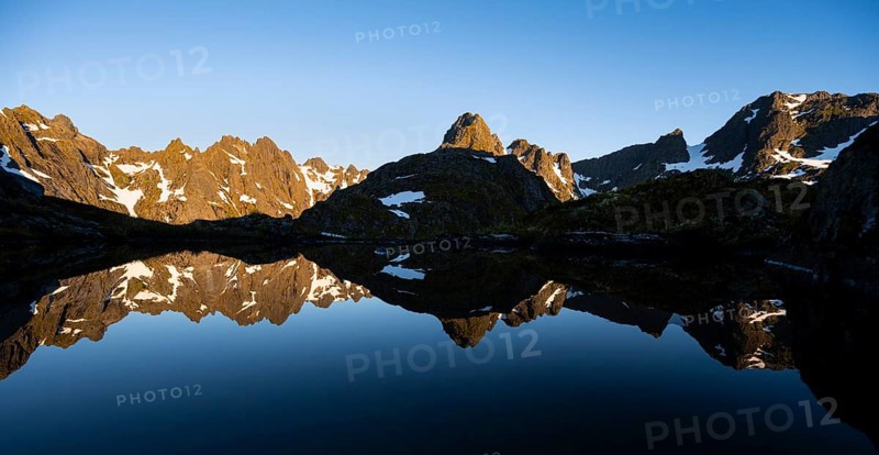Rocky mountain peaks reflected in a small pond, mountain landscape with alpenglow at sunrise, at the Trollfjord Hytta, at the Trollfjord, Lofoten and Vesterålen, Nordland, Norway, Europe