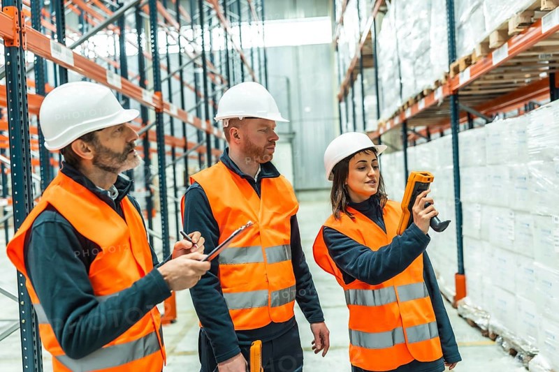 Warehouse workers utilizing barcode scanners and diligently taking notes during logistics operations for efficient inventory management