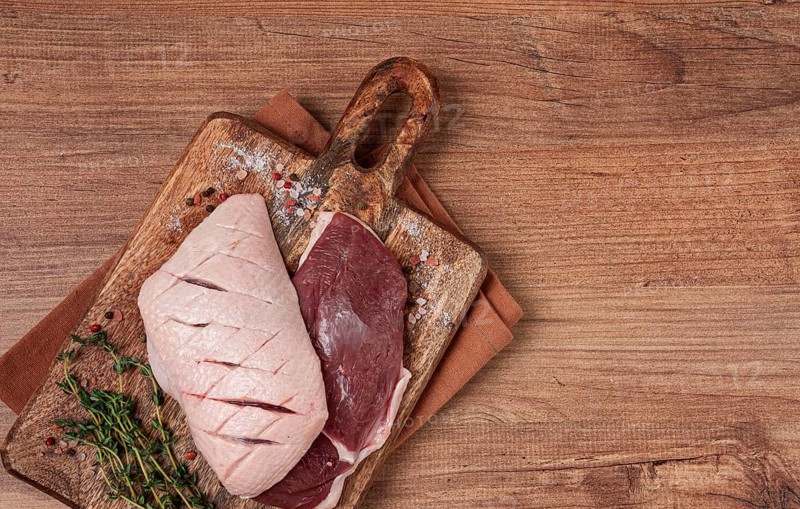 Fresh raw duck breasts, on a wooden chopping board, with herbs and spices, no people