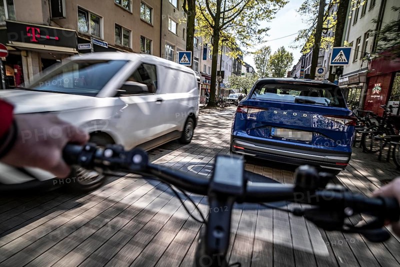Cycling in the city, inner-city street, cycle lane, bicycles have priority, two-lane traffic with parked cars on both sides, cyclists' perspective, Essen, North Rhine-Westphalia, Germany, Europe