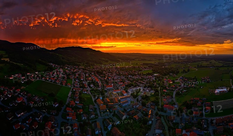 A village under a dramatic sunset sky with glowing clouds and mountains in the background, Bad Feilnbach