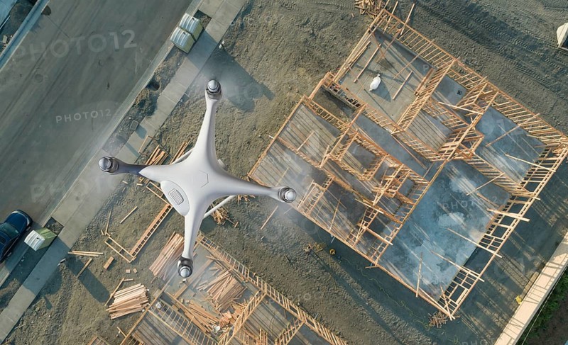 Unmanned aircraft system quadcopter drone UAV in the air over construction site.