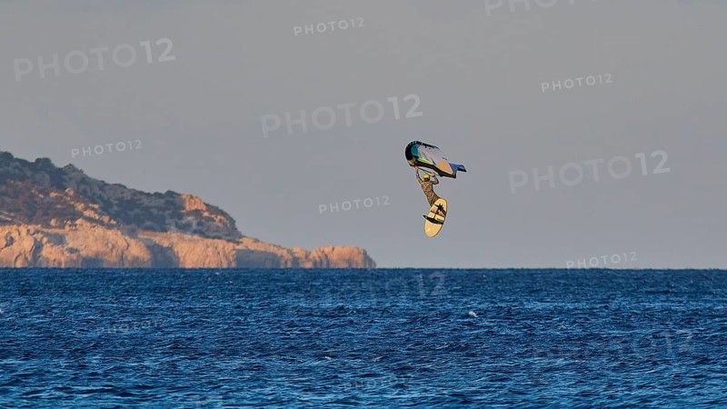 Wingfoiller, surfer in the air over the sea near a coast with cliffs, windsurfer, Meltemi windsurfing spot, Devils Bay, Paralia Vatha, Vatha Beach, southeast coast, Karpathos, Dodecanese, Greek Islands, Greece, Europe