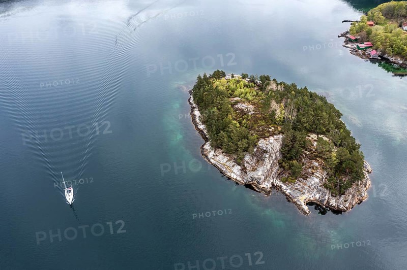 Aerial view topdown on island and sailing boat in the Lysefjord, just north of the Lysefjod bridge, Norway, Europe