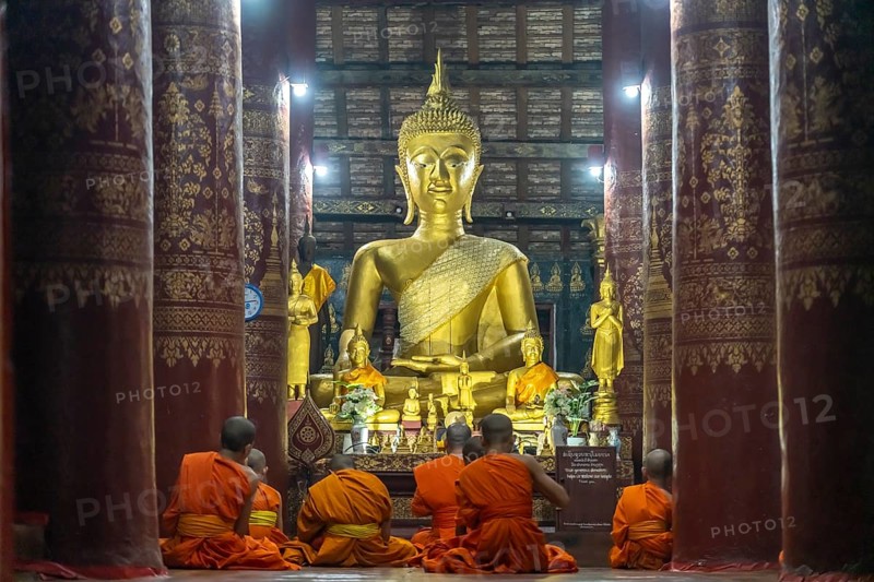 Monks praying in front of the great Buddha in the temple Wat Pak Khan Khammungkhun, Luang Prabang, Laos, Asia