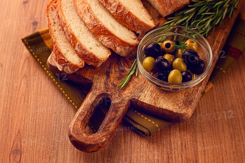 Sliced ciabatta, on a chopping board, with rosemary and olives, Italian bread, close-up, Italian cuisine, breakfast, no people