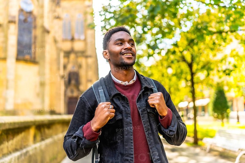 Happy young african man with casual clothes and rucksack enjoying walking in the city