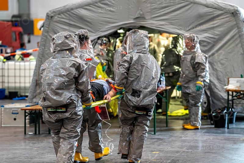 Decontamination of injured persons after an assumed accident involving hazardous substances, fire brigade and aid organisations practise setting up and operating a decontamination station, injured persons are sighted and then washed in a special shower tent to remove possible hazardous substances and chemicals in order to avoid further injuries, the emergency services wear special, ventilated protective suits, large-scale exercise by the Essen fire brigade