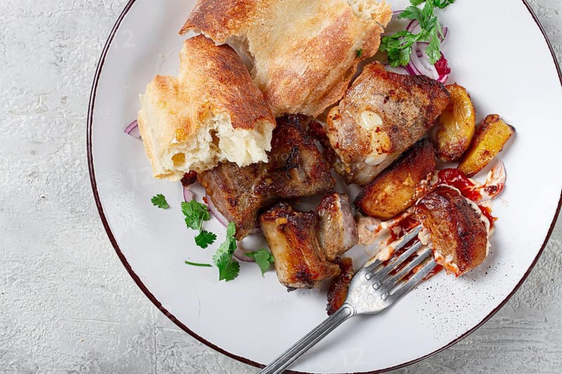 A plate with leftover pork kebab, with bread, on a white plate, close-up, there are no people