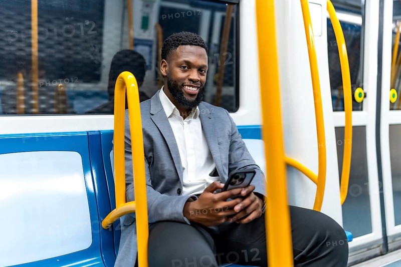Young professional enjoying his commute, using a smartphone while traveling through the metro, exuding confidence and relaxation