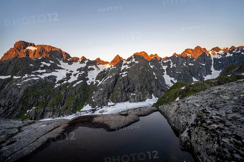 Rocky mountain peaks and Trollfjordvatnet with snow, small pond in moorland at Trollfjord Hytta, mountain landscape with alpenglow at sunrise, at Trollfjord, Lofoten and Vesterålen, Nordland, Norway, Europe