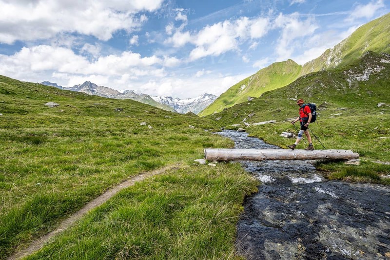 Mountaineer crossing a stream on a tree trunk, mountain landscape with mountain stream, Lasörling Group, Hohe Tauern National Park, East Tyrol, Austria, Europe