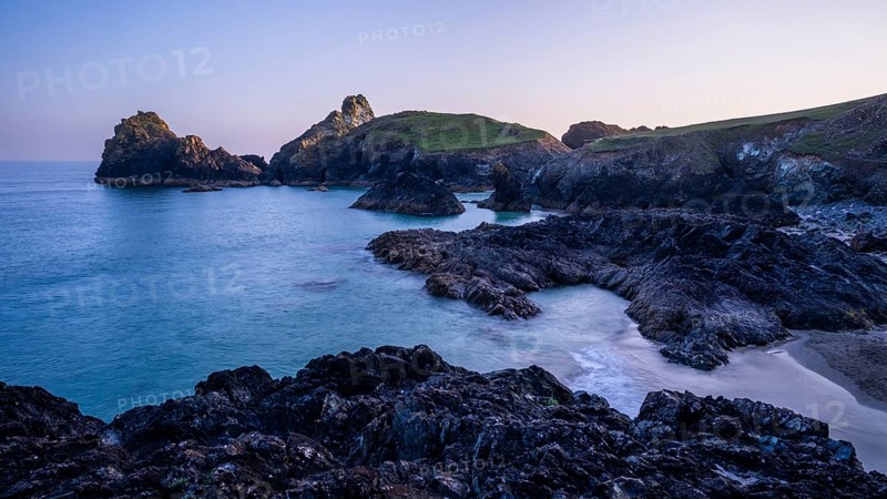 Kynance Cove with Asparagus Island, with sea, sandy beach and rocks in the evening at sunset. Coastal landscape. Long exposure. Good weather, blue sky. Kynance Cove, Lizard Peninsula, Cornwall, England, Great Britain
