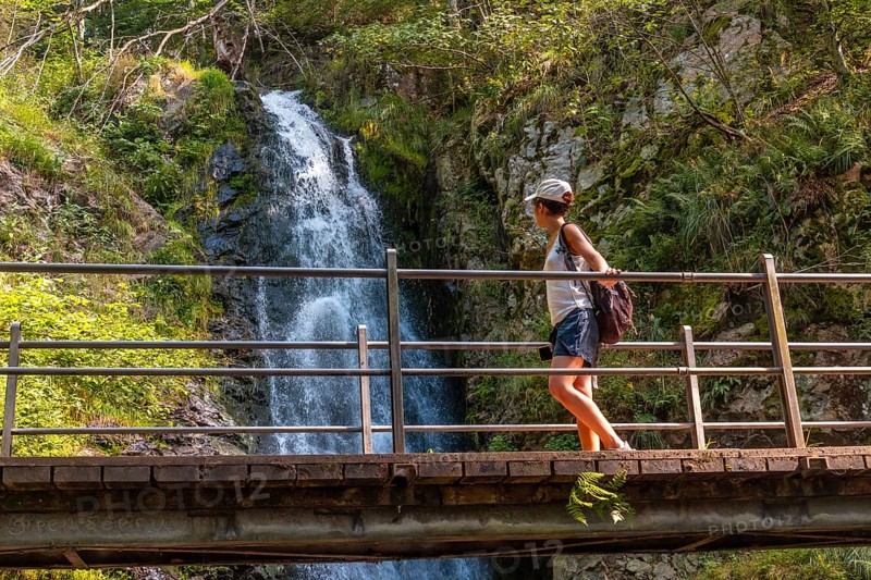 A woman on a wooden bridge at the Todtnau waterfall in the Black Forest in Germany