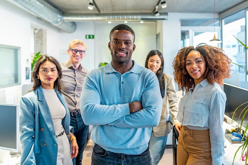 Diverse group of professionals standing together in a modern coworking space, showcasing teamwork and collaboration