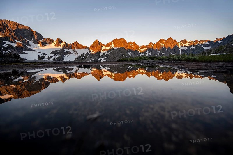 Rocky mountain peaks reflected in a small pond, mountain landscape with alpenglow at sunrise, at the Trollfjord Hytta, at the Trollfjord, Lofoten and Vesterålen, Nordland, Norway, Europe