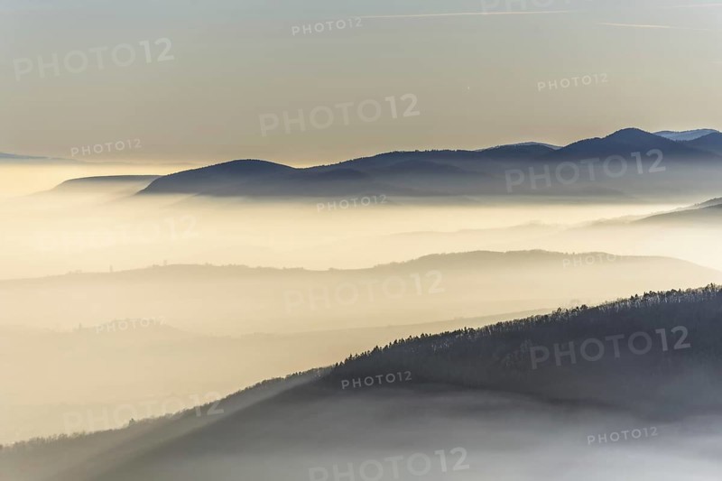 The mountains are shrouded in mist and the sky is a mixture of blue and white. The bleak atmosphere lends the scene a serene and peaceful mood. Bas rhin, Alsace, France, Europe