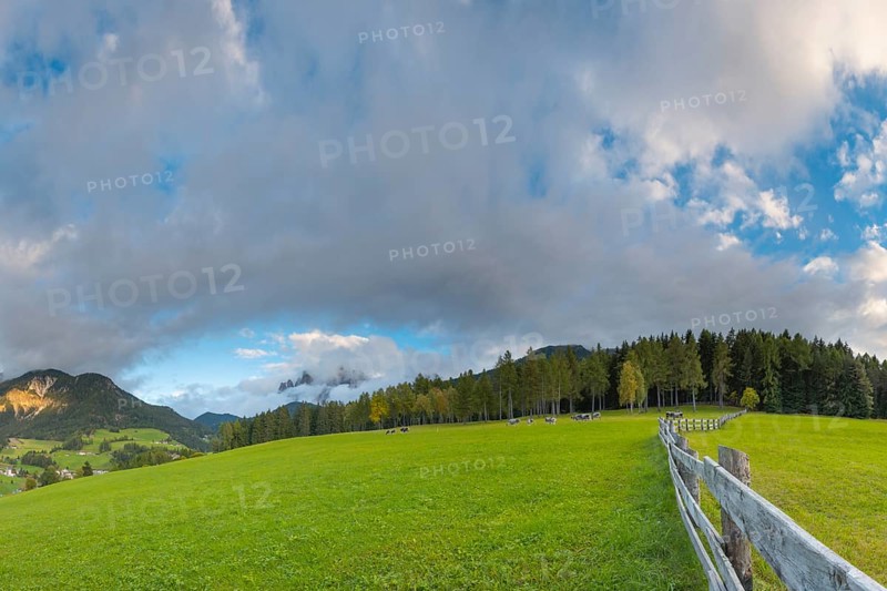 View along a wooden fence across a pasture to the mountains in the evening light, Dolomites, Odle Group, Sasso Putia Group, San Maddalena, Funes, Funes Valley, South Tyrol, Italy, Europe