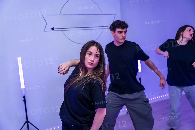 Group of young dancers practicing a modern choreography in a dance studio with neon lights