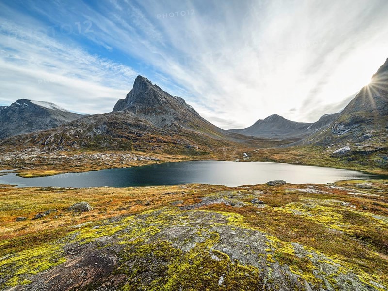 Lake Alnesvatnet with sun star in autumn, mountain Vestre Stigbotthornet in the background, Trollstigen, Reinheimen National Park, Valldalen, Møre og Romsdal, Norway, Europe