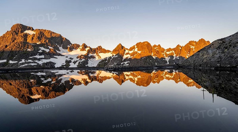 Rocky mountain peaks reflected in a small pond, mountain landscape with alpenglow at sunrise, at the Trollfjord Hytta, at the Trollfjord, Lofoten and Vesterålen, Nordland, Norway, Europe