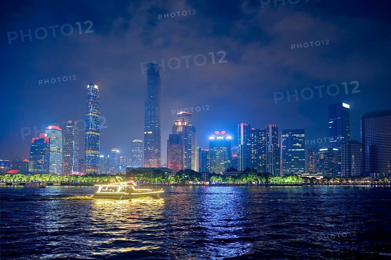 Guangzhou cityscape skyline over the Pearl River with tourist boat illuminated in the evening. Guangzhou, China, Asia