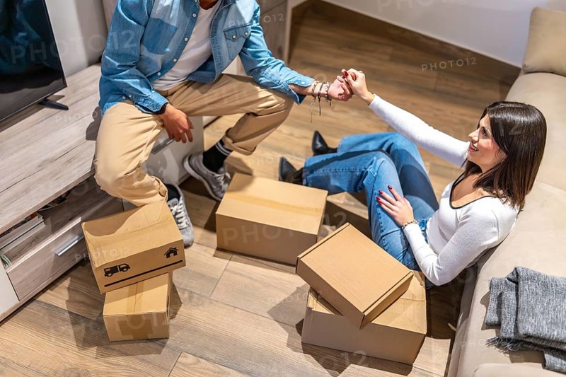 Happy couple holding hands and taking a break from unpacking cardboard boxes in their new home