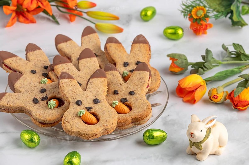 Bunny biscuits with carrots next to orange flowers and Easter bunny