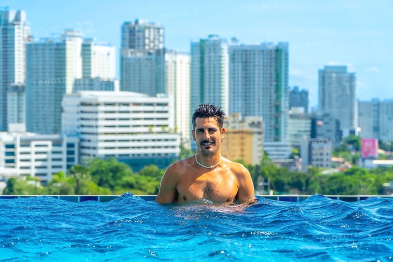 Tourist enjoying refreshing swim in rooftop infinity pool with breathtaking view of cebu city skyline, philippines