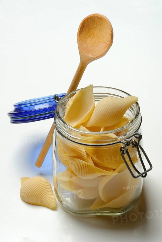 Conchiglione in glass jar with cooking spoon, Italian pasta variety