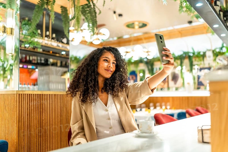 Horizontal photo with copy space of a beauty latin woman smiling taking selfie in a restaurant cafeteria