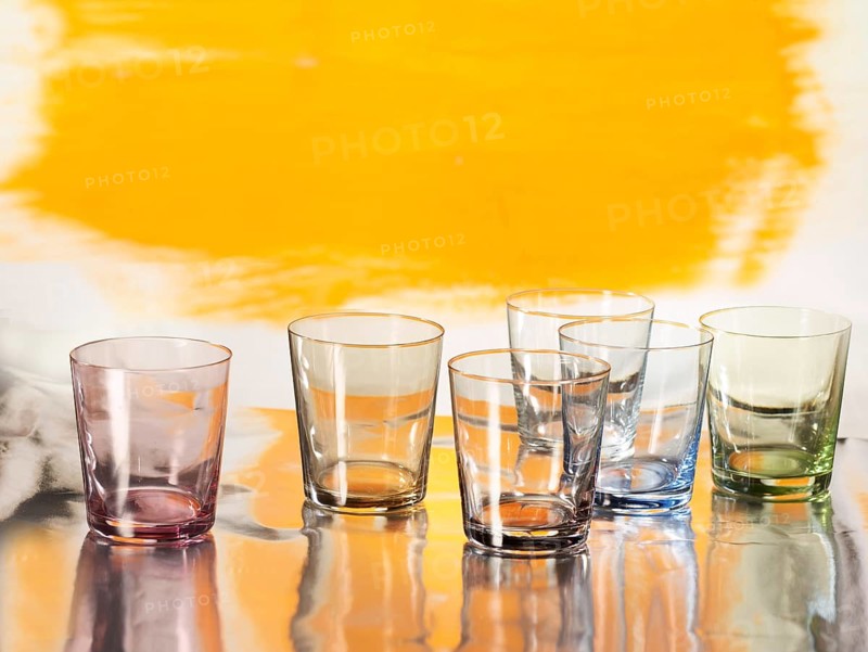 Various glasses on silver foil, yellow coloured surface behind, studio shot