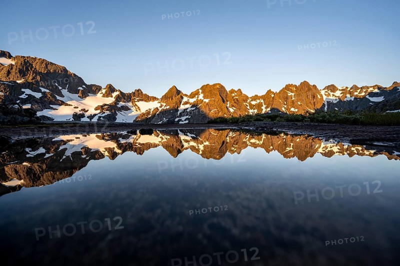 Rocky mountain peaks reflected in a small pond, mountain landscape with alpenglow at sunrise, at the Trollfjord Hytta, at the Trollfjord, Lofoten and Vesterålen, Nordland, Norway, Europe