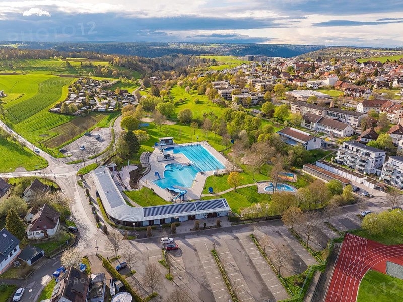 Aerial view of an outdoor swimming pool in an urban landscape with adjacent car park and fields, Calw Stammheim outdoor pool, Calw, Black Forest, Germany, Europe