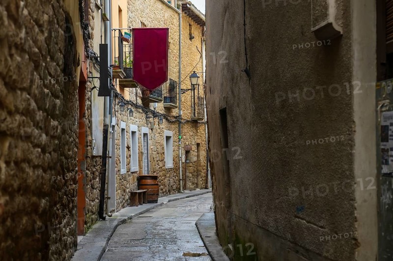 Cobblestone street winding through the charming medieval town of olite, navarre, spain, featuring historic architecture and a vibrant burgundy banner