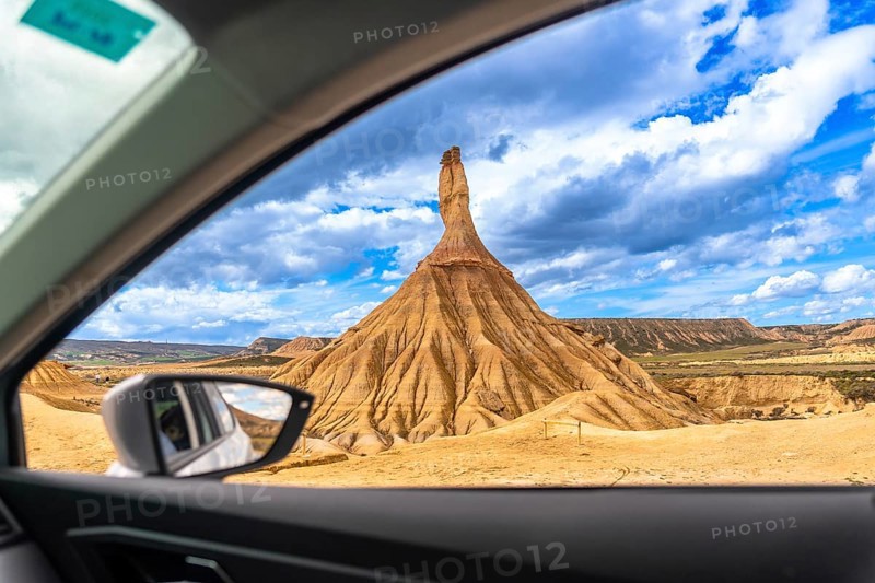 Exploring the breathtaking landscape of bardenas reales natural park in navarre, spain, admiring a unique rock formation from a car window under a cloudy sky