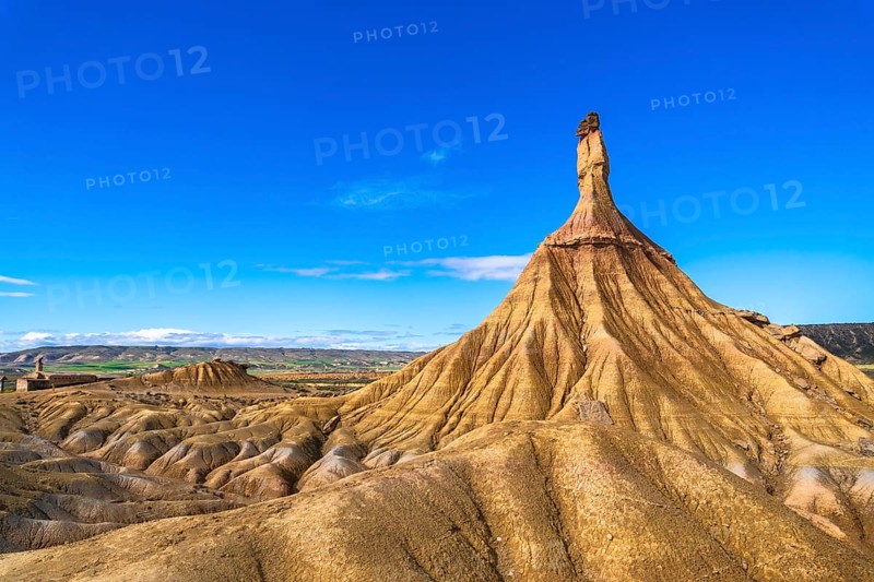 Eroded rock formations create a dramatic landscape in the bardenas reales desert, navarre, spain, under a vibrant blue sky