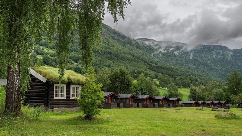 Cloudy forested ridges, wooden huts, Kirketeigen campsite, Kvam, upper Gudbrandsdal, Norway, Europe