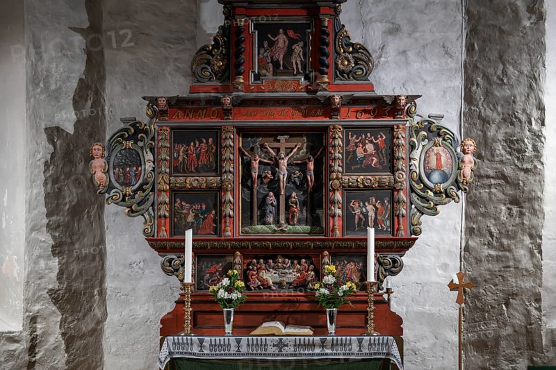 Richly decorated wooden altar in front of a stone wall, adorned with images of saints, candles and flowers, Skedsmo Pilgrims' Church, Skedsmokorset, Norway, Europe