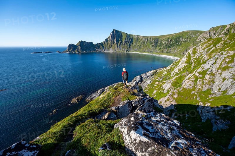 Mountaineer with view of coastal landscape, steep coast with peak Måtind, Høyvika beach and sea, hike to the peak of Måtind, Andøya island, Vesterålen, Nordland Norway
