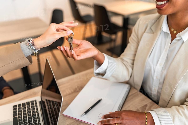 Real estate agent handing over keys to a new homeowner, symbolizing a successful property purchase
