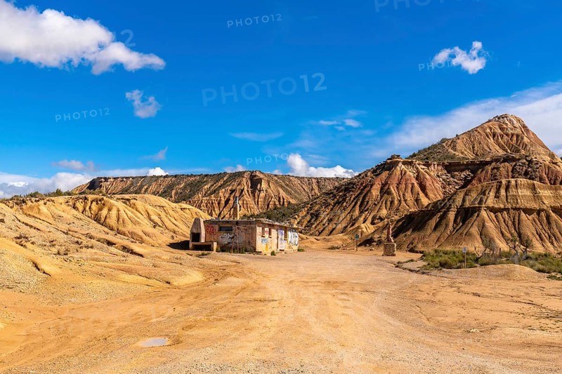 Scenic view of an abandoned, graffiti covered building rising from the arid bardenas reales desert in navarre, spain, under a vivid blue sky