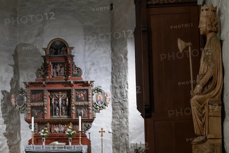 Richly decorated wooden altar in front of a stone wall, decorated with images of saints, wooden sculpture of Olav the Saint or Olav II Haraldsson with axe, Skedsmo Pilgrim Church, Skedsmokorset, Norway, Europe