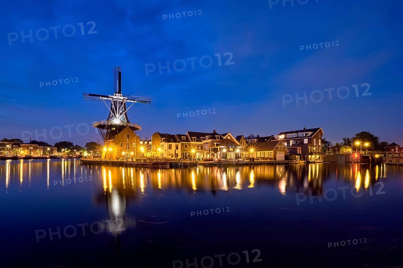 View of Harlem cityscape with landmark windmill De Adriaan on Spaarne river in the night illuminated. Harlem, Netherlands