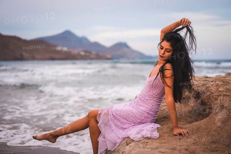 Portrait of a young brunette Caucasian woman in a pink cloth dress, on the beach by the sea in Cabo de Gata, Nijar