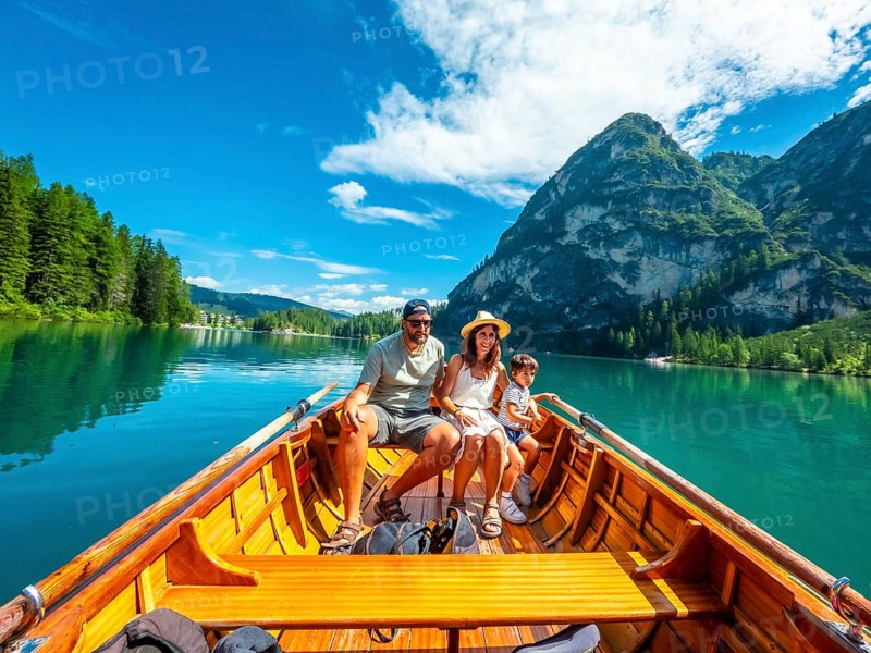 Family enjoying a sunny summer day rowing a wooden boat on the crystal clear waters of lake braies, surrounded by stunning dolomite mountains